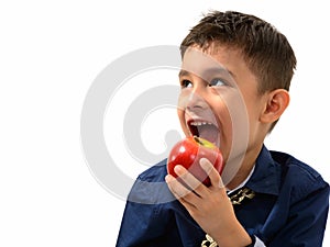 Studio shot of cute happy boy smiling and eating apple while thi