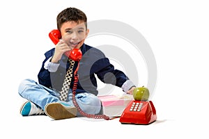 Studio shot of cute happy boy smiling while talking on old telep