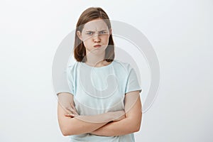 Studio shot of cute mad or offended female with flapped ear sulking and frowning crossing arms on chest standing in photo