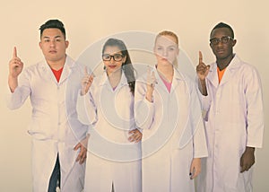 Studio shot of diverse group of multi ethnic doctors pointing finger up together