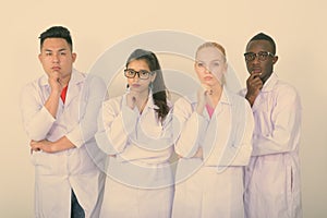 Studio shot of diverse group of multi ethnic doctors thinking with hand on chin together