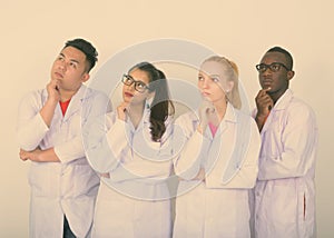 Studio shot of diverse group of multi ethnic doctors thinking while looking up together