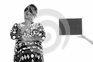 Studio shot of fat black African woman thinking with blank blackboard