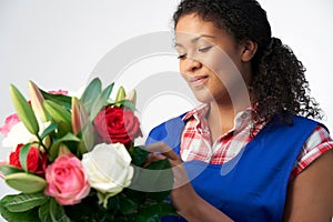 Studio Shot Of Female Florist Arranging Bouquet Of Lillies And Roses Against White Background