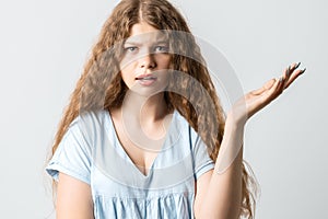 Studio shot of frustrated female with curly long hairstyle gesturing with raised palm