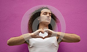 Studio shot of a gay man doing heart symbol shape with hands  on purple background