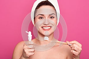 Studio shot of good looking young woman holding brush and tooth paste for teeth cleaning in hands. happy smiling girl with