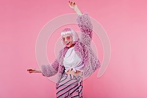 Studio shot of gorgeous young woman in periwig dancing with smile. Portrait of beautiful lady with