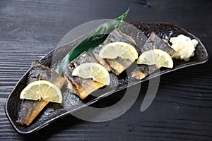 Studio shot of grilled atka mackerel with lemon on dark background