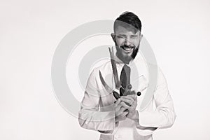 Studio shot of a happy bearded young chef holding sharp knives o