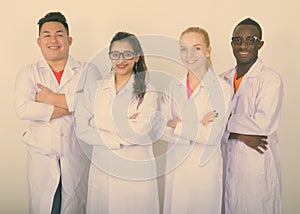 Studio shot of happy diverse group of multi ethnic doctors smiling with arms crossed together