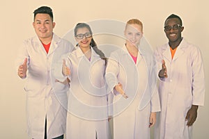 Studio shot of happy diverse group of multi ethnic doctors smiling while giving handshake together