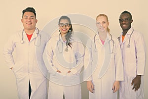 Studio shot of happy diverse group of multi ethnic doctors smiling and standing together