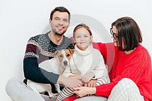 Studio shot of happy family of three family members and dog, embrace and smile happily, have good relationships, isolated on whit