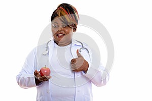 Studio shot of happy fat black African woman doctor smiling whil