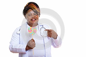 Studio shot of happy fat black African woman doctor smiling whil