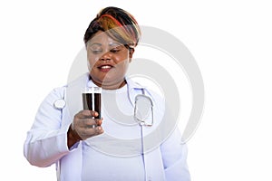 Studio shot of happy fat black African woman doctor smiling whil