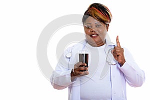 Studio shot of happy fat black African woman doctor smiling whil