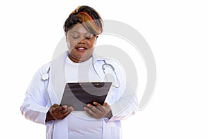 Studio shot of happy fat black African woman doctor smiling whil