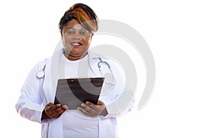 Studio shot of happy fat black African woman doctor smiling whil