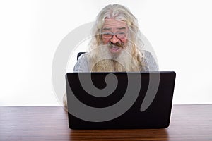 Studio shot of happy senior bearded man smiling and laughing whi