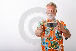 Studio shot of happy senior bearded tourist man smiling while gi