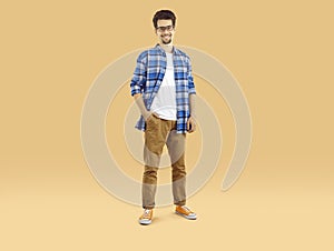 Portrait of a happy male student in glasses and casual clothes standing on a studio background