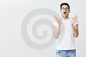 Studio shot of impressed and surprirsed charismatic young white man in glasses standing right side of copy space