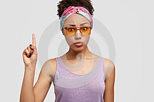 Studio shot of indignant puzzled Afro American lady looks with worried expression at camera, points with index finger