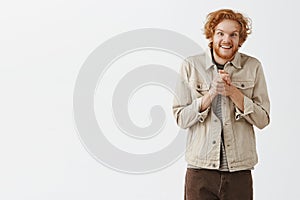 Studio shot of insane or crazy weird redhead guy with messy hair and beard staring with strange sick look rubbing hands