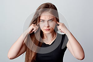 Studio shot of an irritated woman because loud noise against grey background