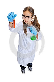 Studio shot of little cute girl, kid in white big gown as chemist, scientist doing experiment with colored chemical