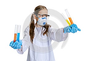 Studio shot of little cute girl, kid in white big gown as chemist, scientist doing experiment with colored chemical