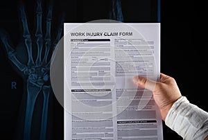 Studio shot of man reading work injury claim form with a wrapped hand on top of an X-ray film medical and insurance concept no