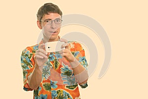 Studio shot of man taking picture with mobile phone