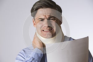 Studio Shot Of Man Wearing Neck Brace Reading Letter