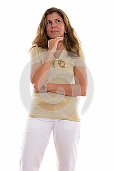 Studio shot of mature beautiful woman standing and thinking whil