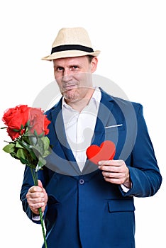 Studio shot of mature businessman holding red roses and heart re