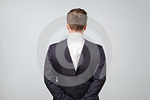 Studio shot of a mature caucasian man wearing his suit on backwards, gray background