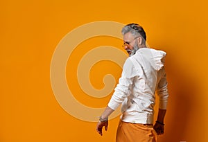 Studio shot of modern, hipster businessman pretends dancing, isolated on orange background