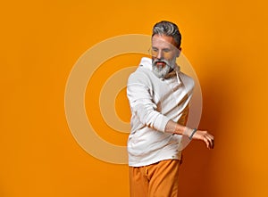 Studio shot of modern, hipster businessman pretends dancing, isolated on orange background