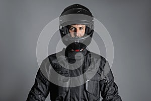 Studio shot of Motorcyclist biker in black equipment looking at camera.