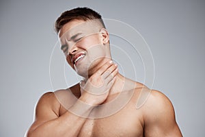 I went too far this time. Studio shot of a muscular young man experiencing neck pain against a grey background.