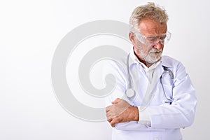 Studio shot of sad senior bearded man doctor thinking while wear