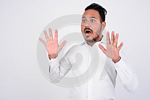 Studio shot of scared bearded Indian businessman looking shocked