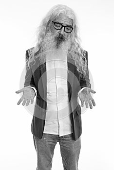 Studio shot of senior bearded businessman standing while shrugging