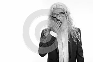 Studio shot of senior bearded businessman thinking while looking shocked