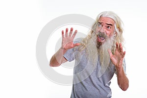 Studio shot of senior bearded man looking scared while showing s