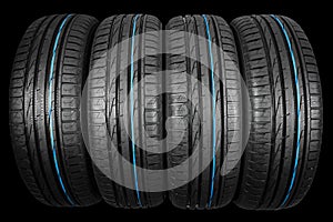 Studio shot of a set of summer car tires on black background. Tire stack background. Car tyre protector close up. Black rubber tir