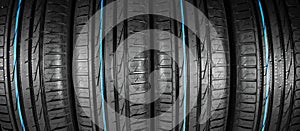 Studio shot of a set of summer car tires on black background. Tire stack background. Car tyre protector close up. Black rubber tir